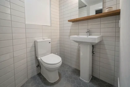 Deuxième salle de bain compacte et moderne avec toilette blanche et carrelage gris dans une maison familiale